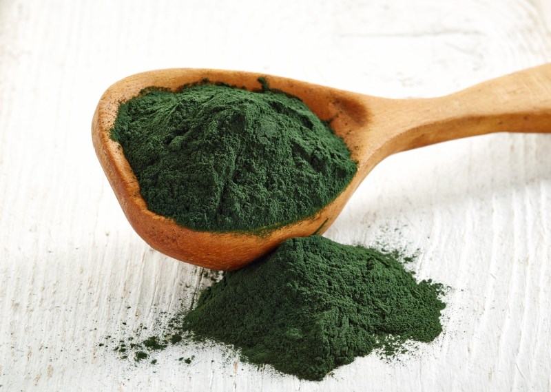 Beanbag-Wooden spoon of spirulina algae powder on wooden background